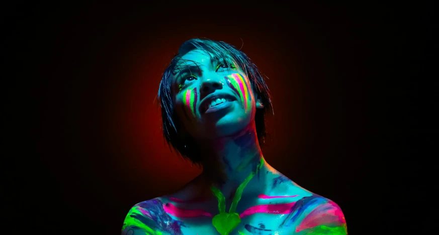 a woman covered in neon paint posing for the camera