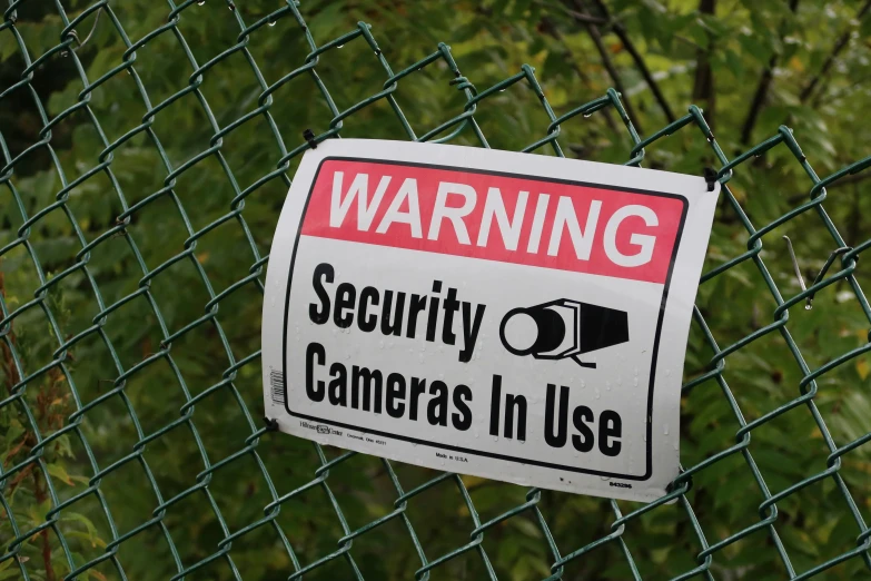 a close up of a security sign on a fence