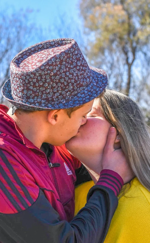 the boy and girl are kissing each other on the park bench