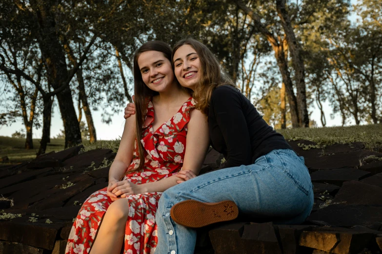 a couple of girls sit next to each other on some logs