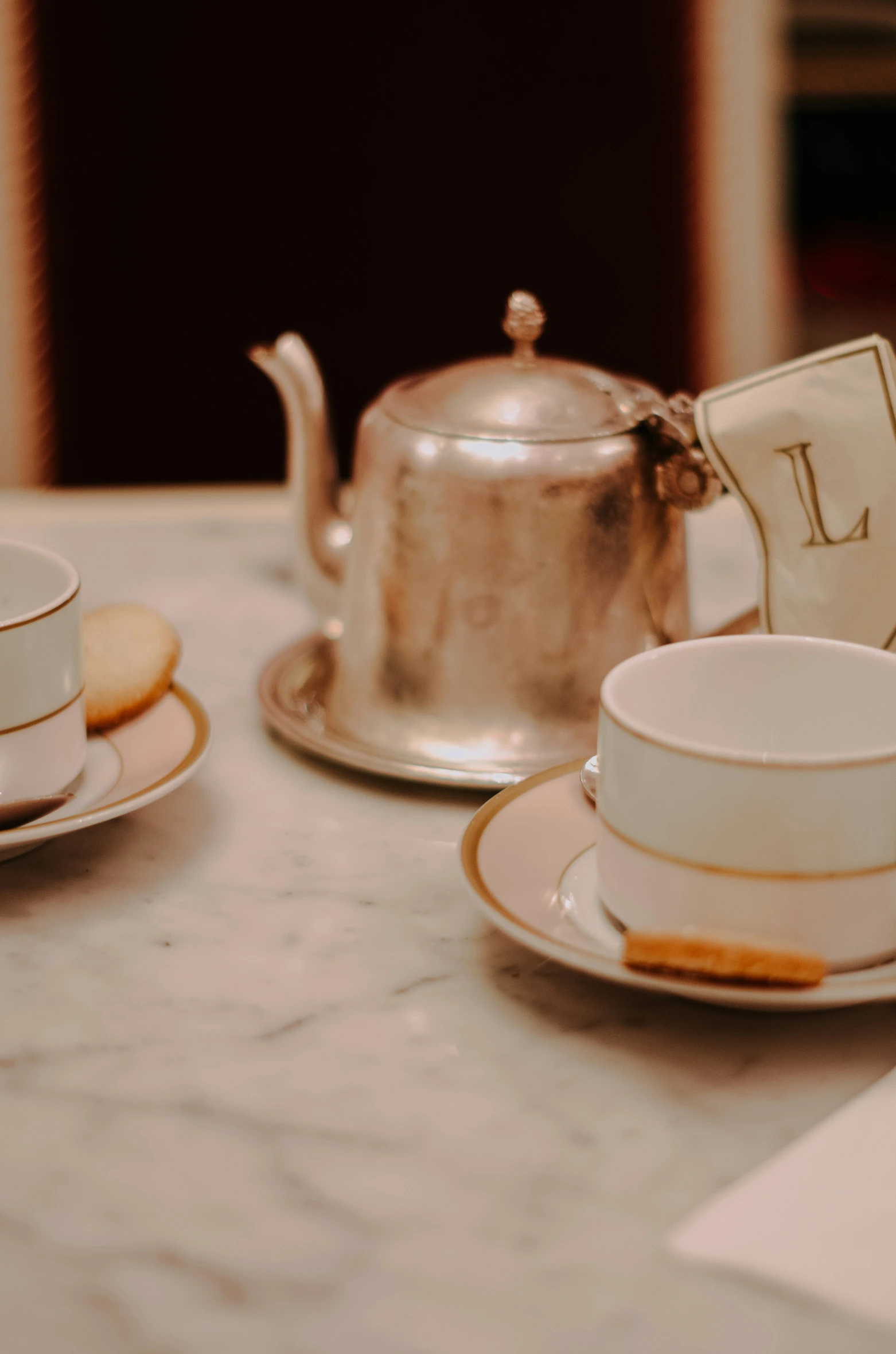 cups, a tea kettle and two cookies on a table