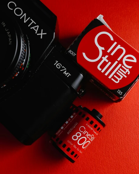 two different colored digital cameras sitting on a red surface