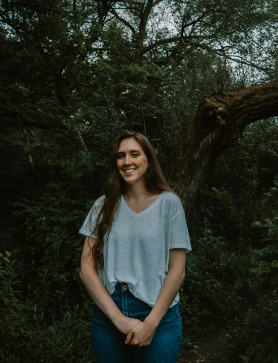 a beautiful young woman standing in front of a tree