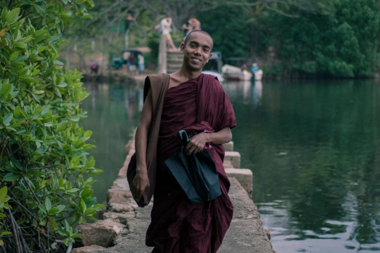 a man in a red robe standing on a river edge