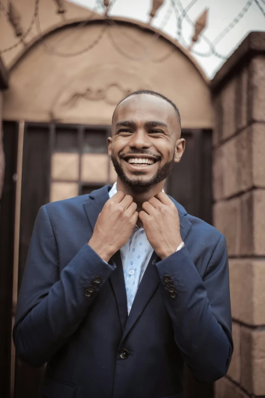 a man smiling wearing a blue jacket and tie