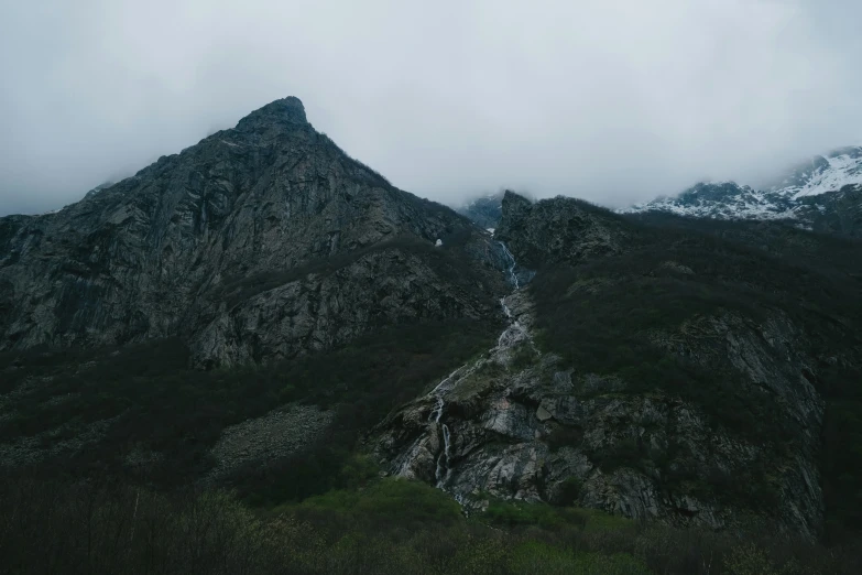 mountains rise very high into the clouds with one of them growing off the side