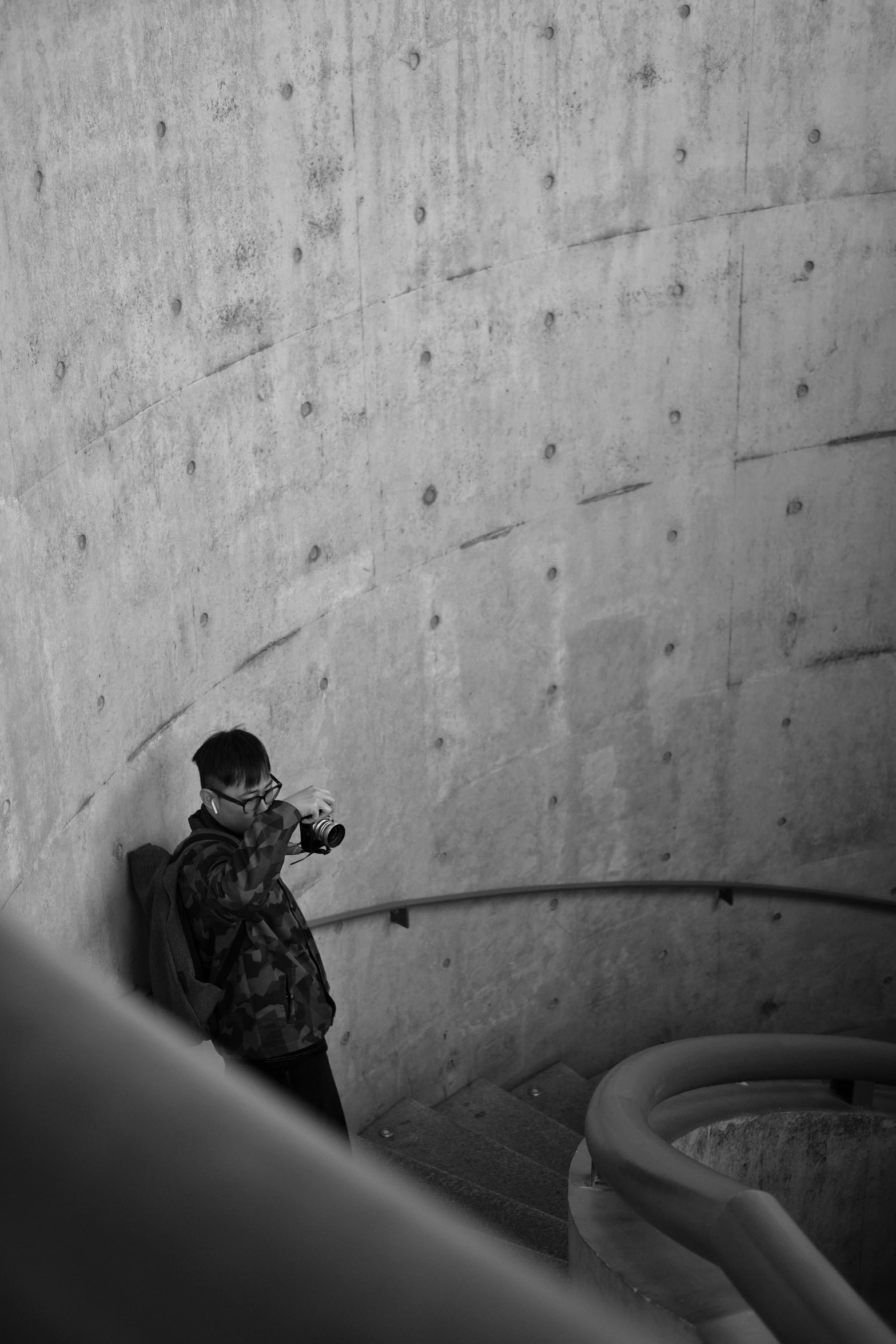 black and white pograph of man with camera near wall