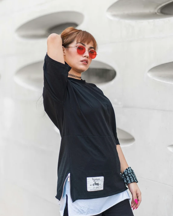 woman in black outfit, sunglasses and wrist watches near wall