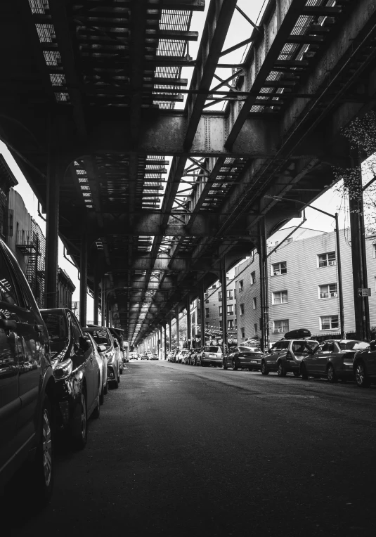 a street with several cars parked in it and metal structure over the road