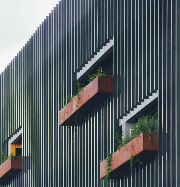 three planters with plants on the balcony of an office building