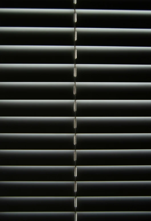 a dark background with horizontal blind blinds in grey and white