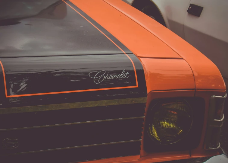 the front grill and headlights of an orange muscle car