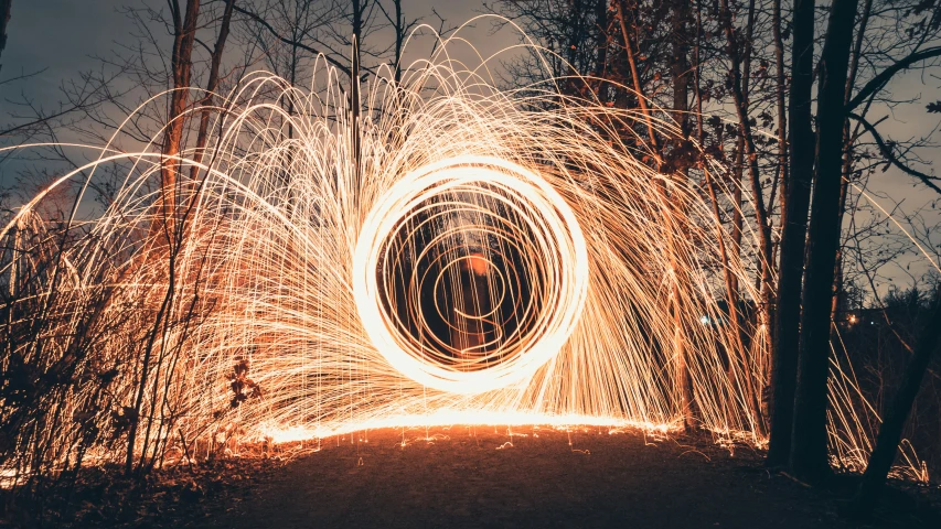 a light emitting image of swirling steel wool in the woods