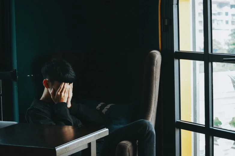 person sitting in chair with laptop near window