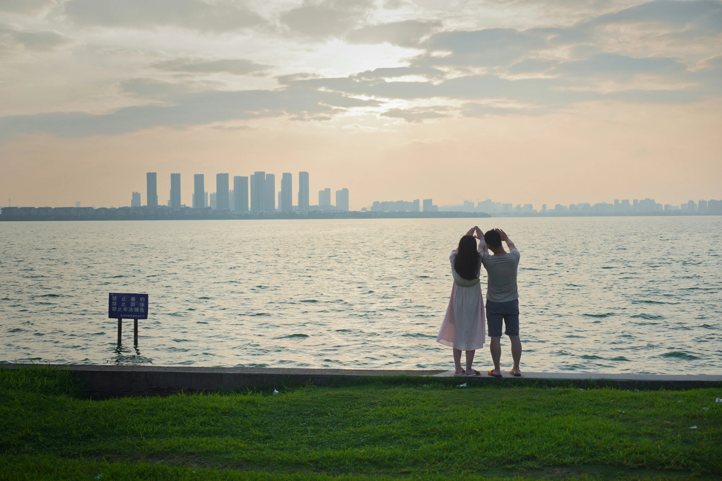 two girls are standing by the edge of the water in front of a city skyline