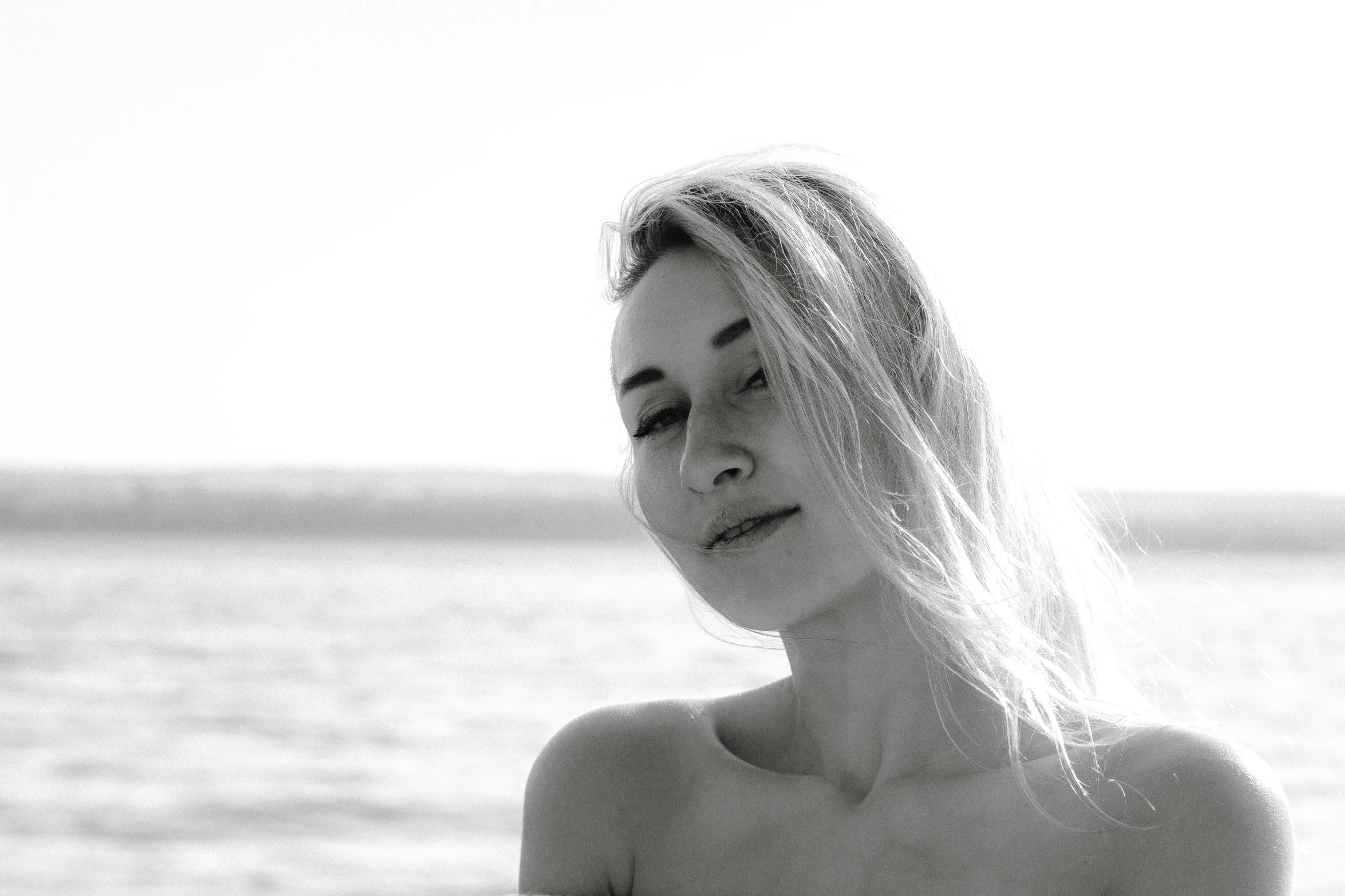 a woman with long white hair standing next to the ocean