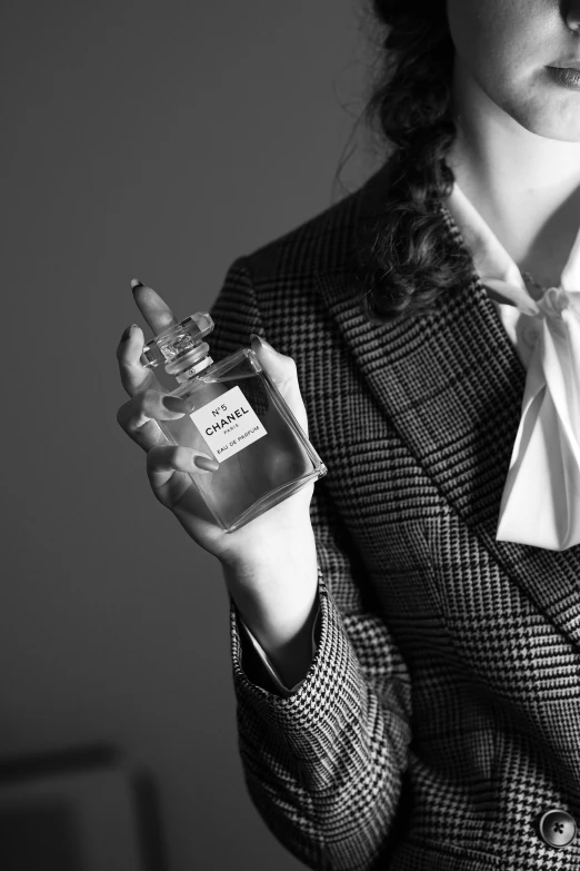a woman holding an open perfume bottle in her hand