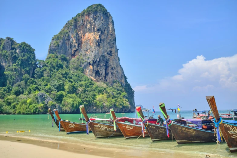 a group of wooden boats tied to a sandy shore