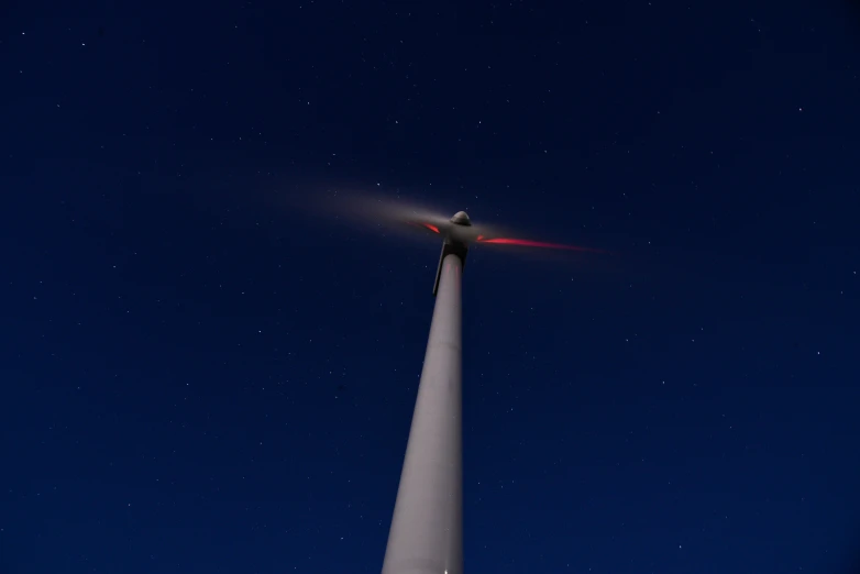 a tall pole with a light shining on it and stars in the sky behind