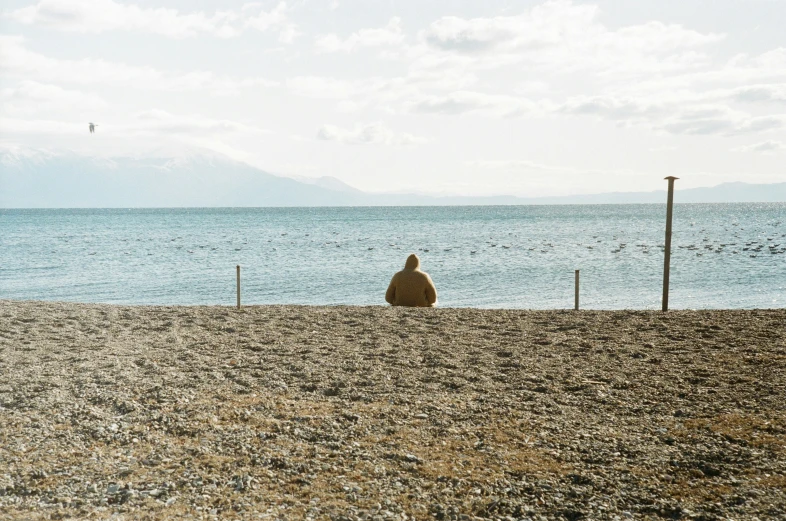 a person sits on the beach and looks out at the water