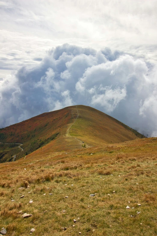 a hill on the side of a grassy area covered in clouds