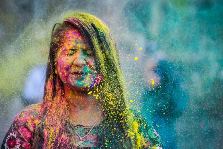 a  covered in paint with her long hair colored powder is sprinkled all around her face