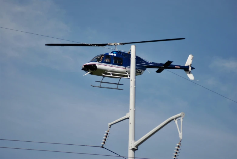 the helicopter is flying very high above the power lines