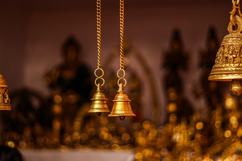 golden bells hanging in front of a statue of an old man