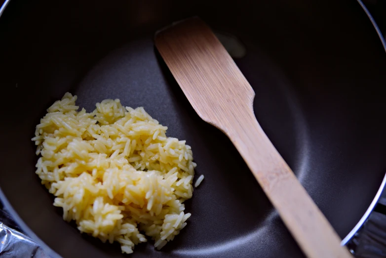 some rice and a wooden spoon in a black pan