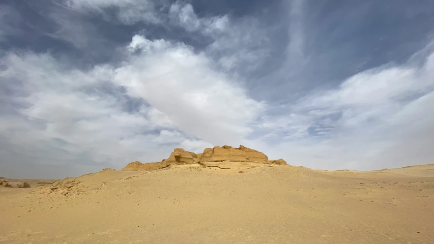 a large hill of sand with blue sky above it