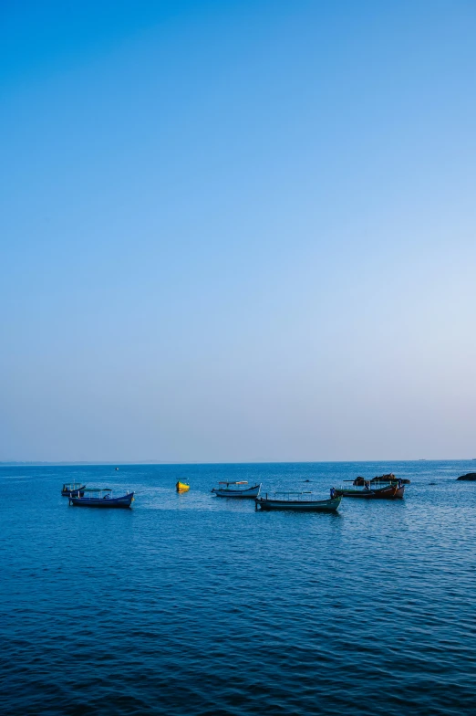 small boats in the ocean with a light house behind them