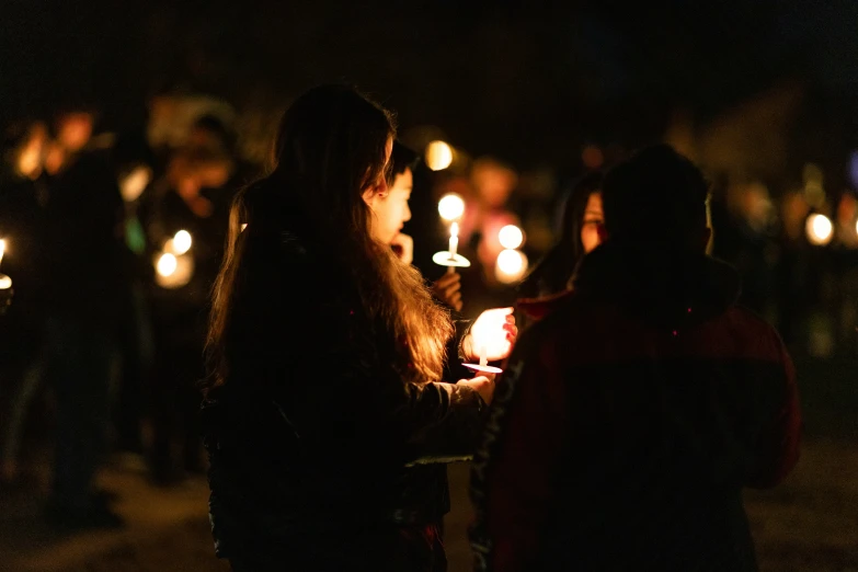 two woman standing near each other in front of a candle