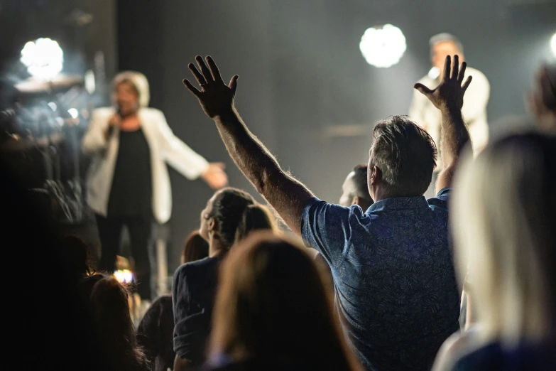 people at an event raising their hands up