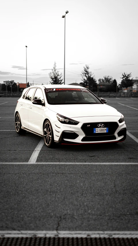 a white car with black and red rims parked in a parking lot