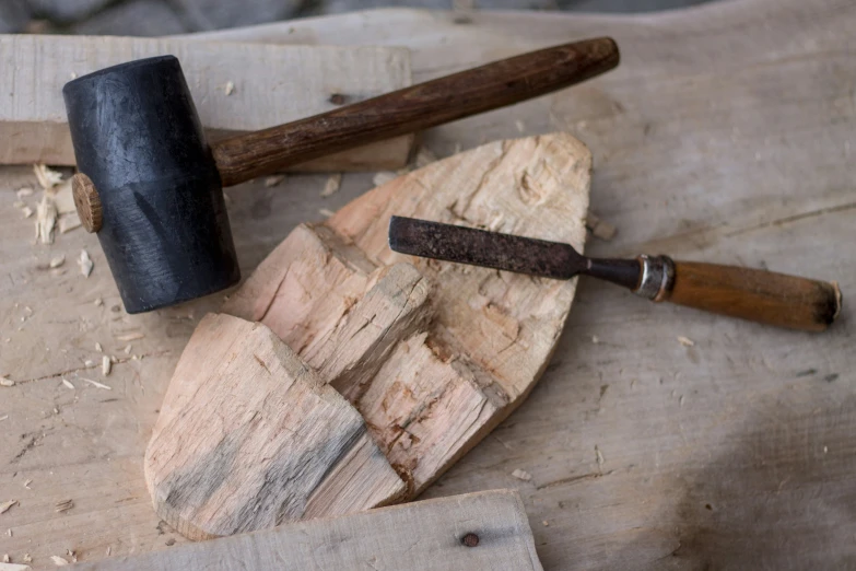 a wooden  board topped with three types of wood and some kind of knife