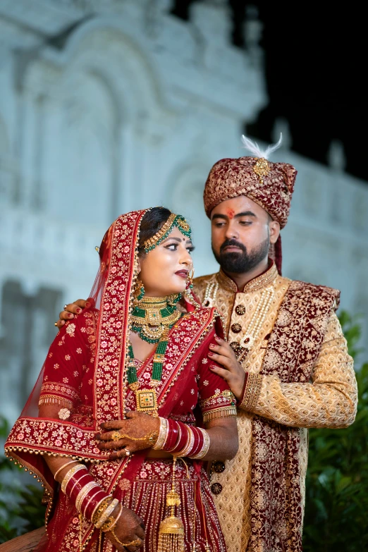 indian bride and groom posing outside of a temple