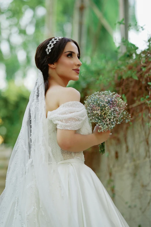 a woman wearing a veil holds a bouquet of flowers