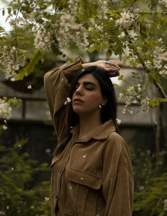 young woman in brown shirt holding hands behind her head