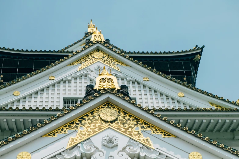 the roof of an asian style building with an ornate gold and white design on it