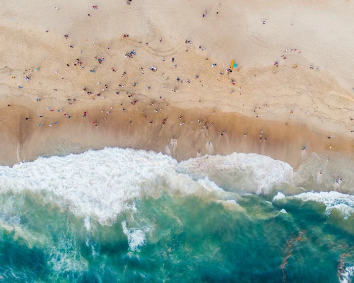 a po taken from a high altitude point of view shows the sand, water and ocean with a beach area with people standing on it