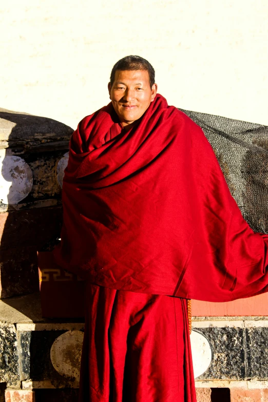 a smiling man dressed in a red robe