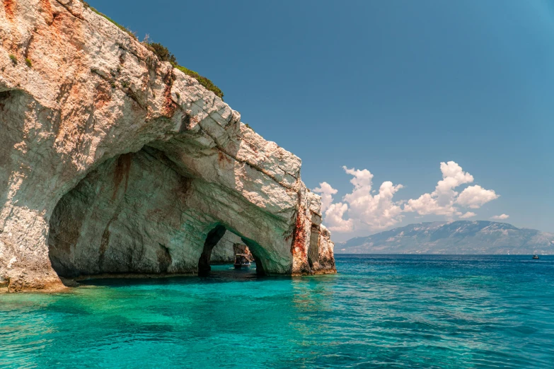 there is a rock and water next to the blue ocean