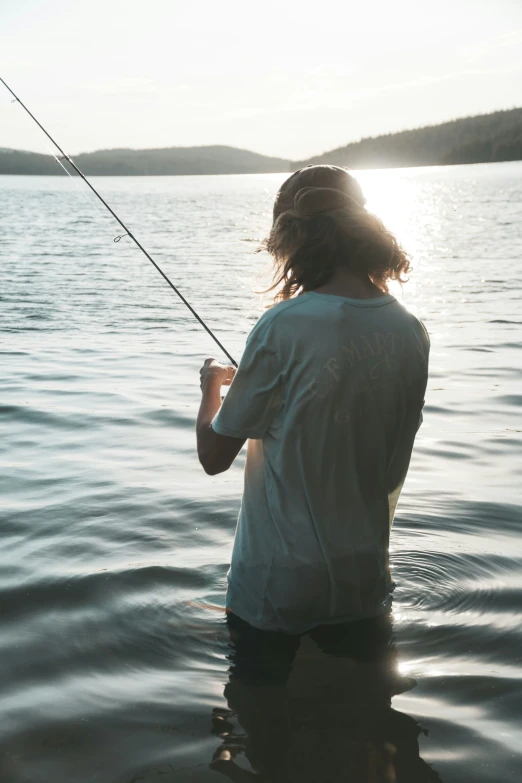 a person standing in the water while holding onto a fishing pole