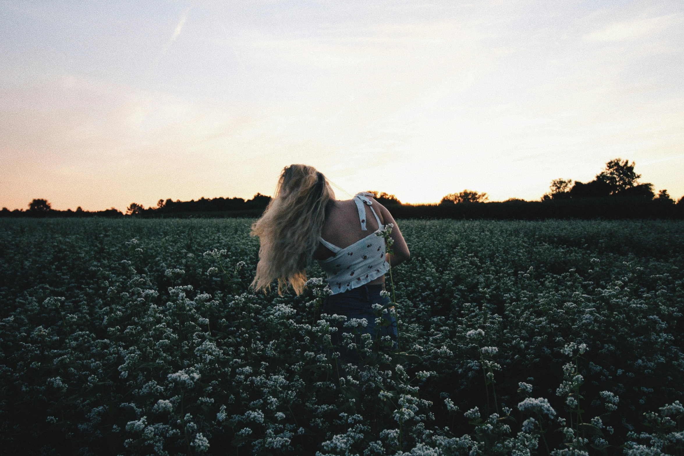 a woman in a field standing with her back turned