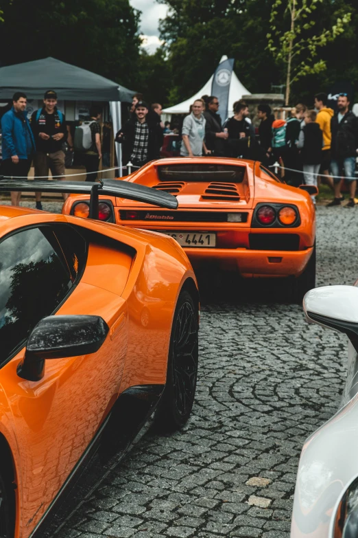 orange sports cars at an event on the street