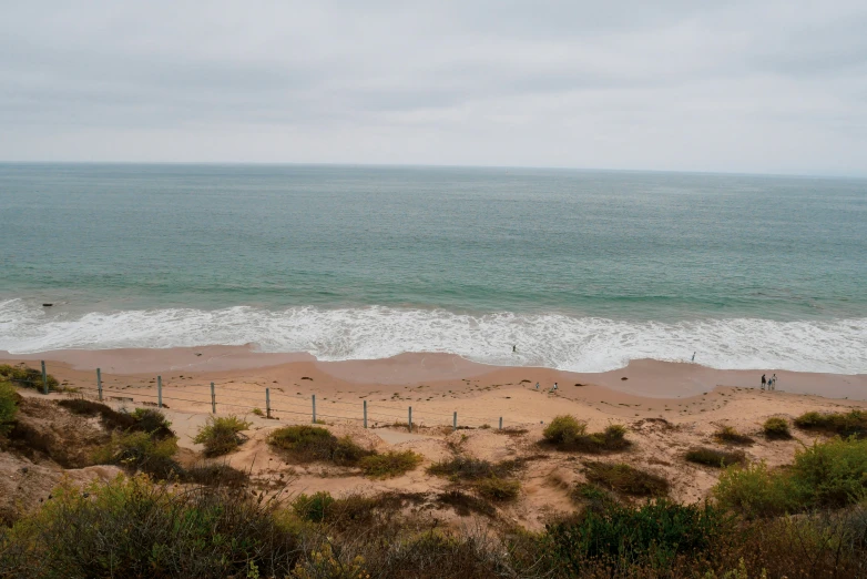 an empty beach is seen under a cloudy sky