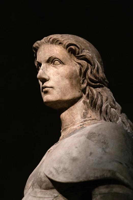 a statue with long hair wearing a gray cloak