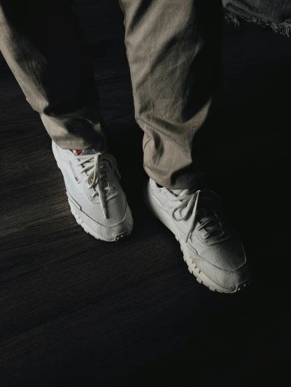 a person's legs wearing sneakers on top of a wooden floor