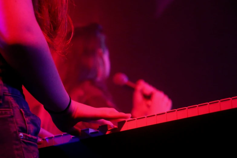 person playing keyboard in dark room with red lighting