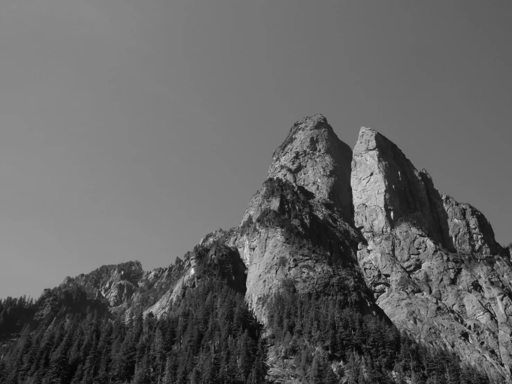 a mountain with a forest at the base under a cloudy sky